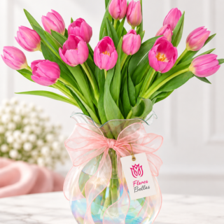 Tulipanes fucsia en florero de cristal tornasol con moño rosa