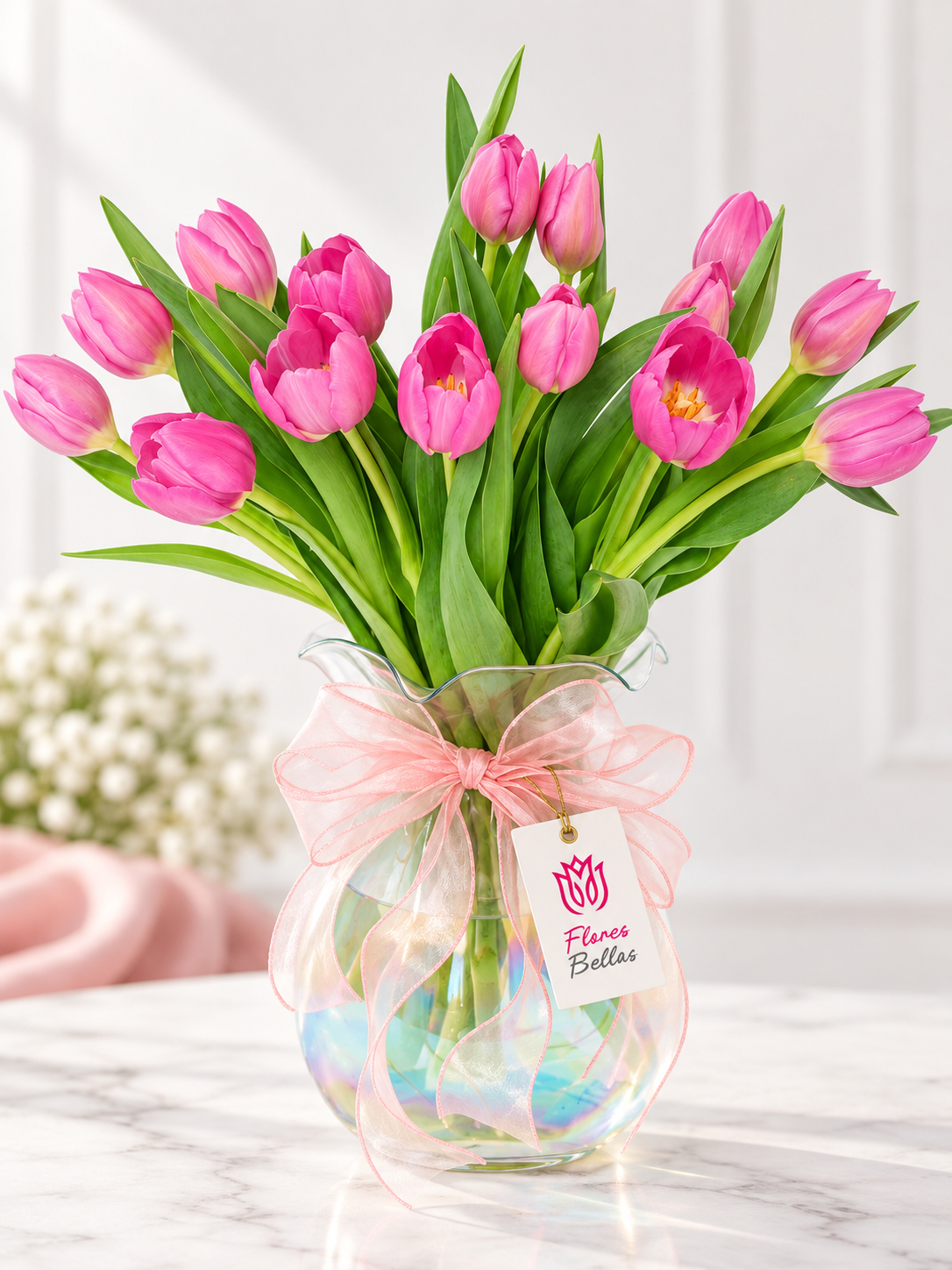 Tulipanes fucsia en florero de cristal tornasol con moño rosa